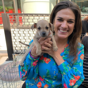 A women in a blue shirt with an adorable puppy.
