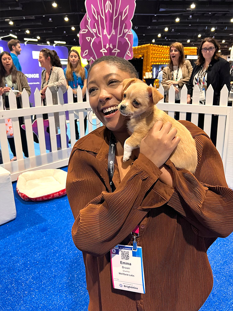 A Puppy Love employee with a puppy at a tradeshow booth event.