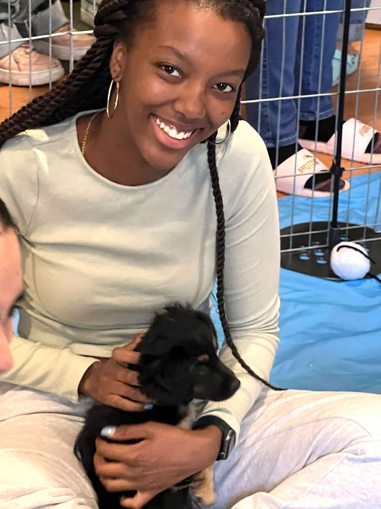 A girl holding a black puppy - Puppy Love is the best workplace wellness ideas in Los Angeles to San Diego, CA.
