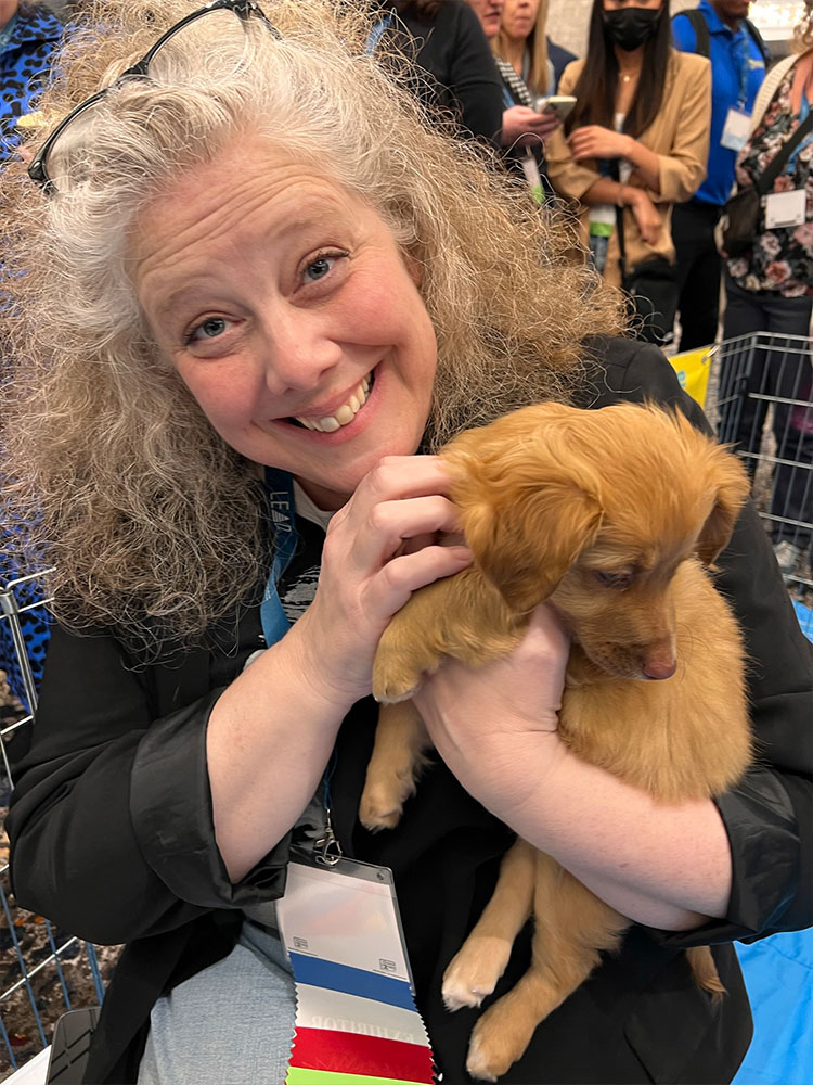 A woman holding an adorable puppy at a Puppy Love puppy lounge!