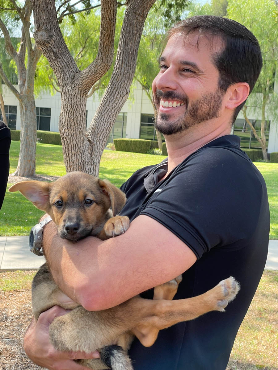 A man holding an adorable puppy at a Puppy Love™ Southern California event - boosting his happiness and engagement.