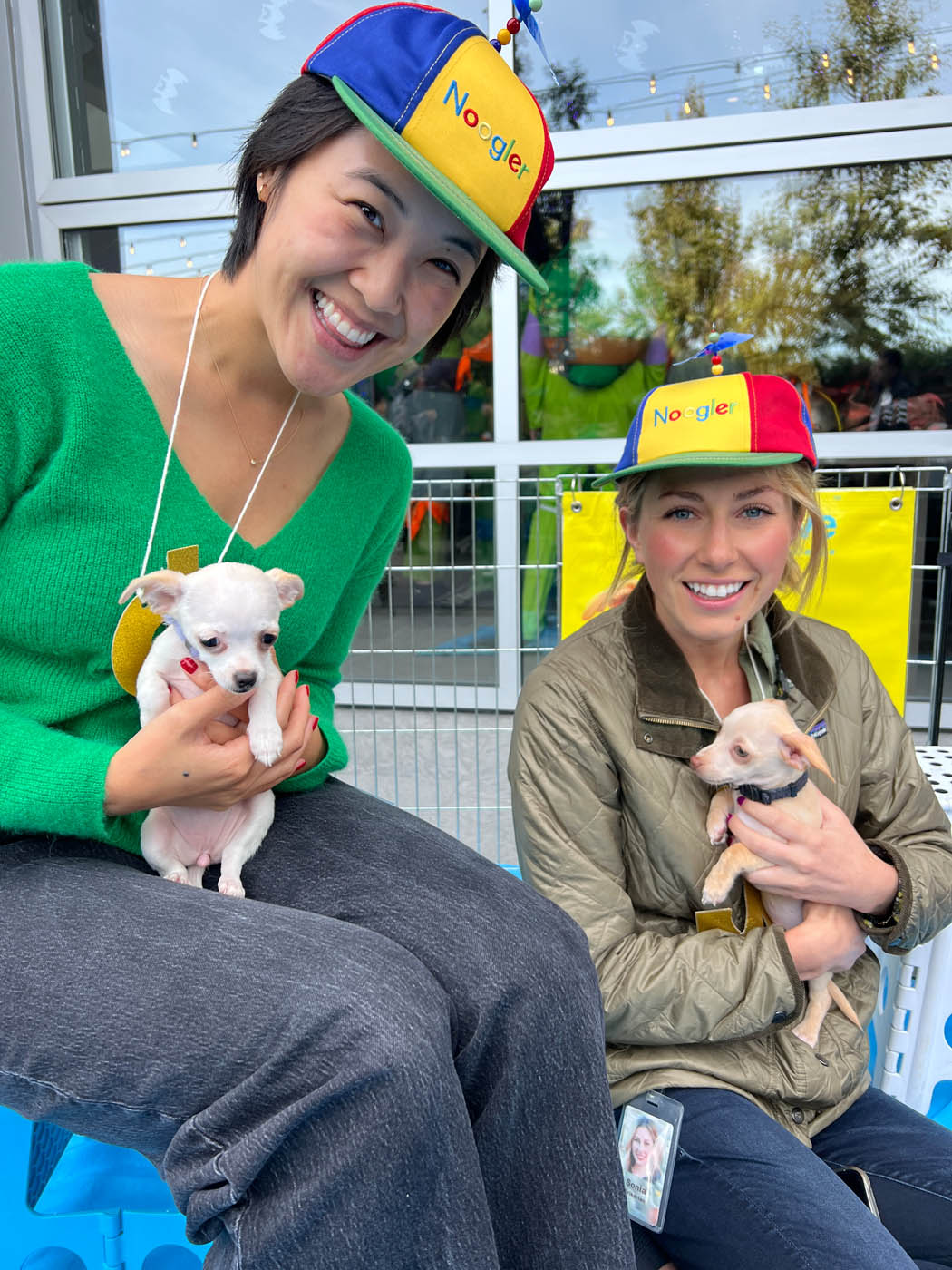 Two girls in google hats holding puppies and loving the joy that Puppy Love brings!